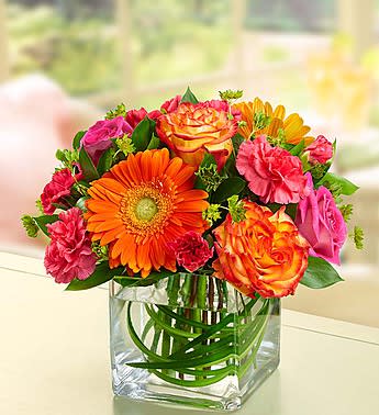 Bright mixed bouquet in a clear square glass vase