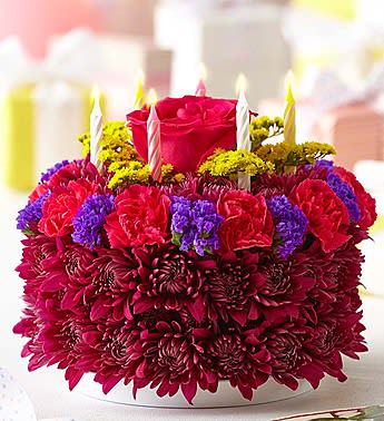 Round floral cake with candles and a red rose on top