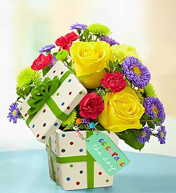 Bouquet of yellow roses, red carnations, and purple daisies in a gift box