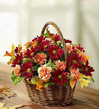 Basket of red and peach flowers with autumn leaves