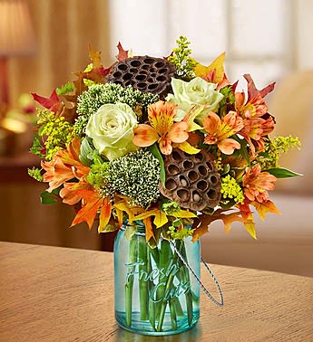 Autumn bouquet with white roses and orange flowers in a blue glass vase