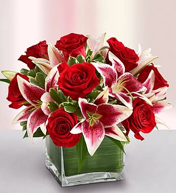 Red roses and pink lilies in a square glass vase