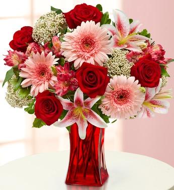 Bouquet of red roses, pink gerbera daisies, and lilies in a red vase