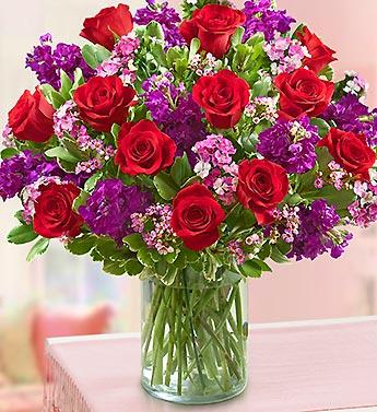 Bouquet of red roses and purple flowers in a glass vase