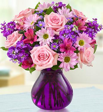 Pink roses and purple daisies in a purple glass vase