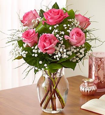 Pink roses arranged in a clear glass vase with baby's breath.