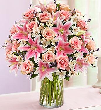 Pink roses and lilies arranged in a clear glass vase