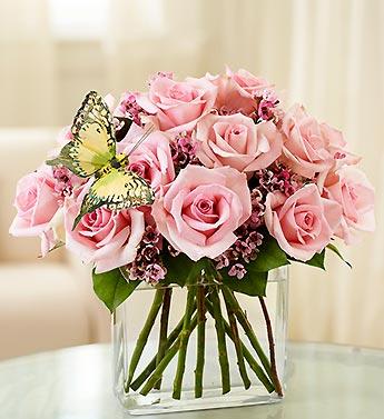 Pink rose bouquet in a clear glass vase with a butterfly decoration