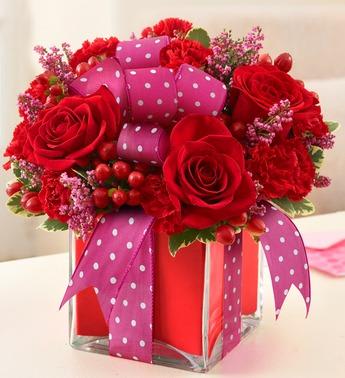 Red roses and pink ribbon in a square glass vase