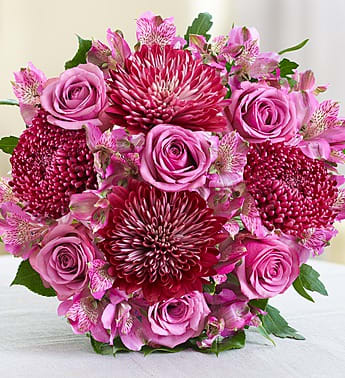 Pink roses and burgundy chrysanthemums arranged in a round bouquet.