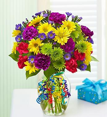 Colorful mixed bouquet in a glass vase with curly ribbon