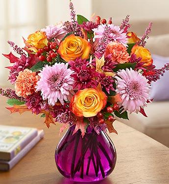 Mixed bouquet of orange roses and pink daisies in a purple vase