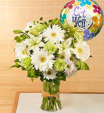 White daisy and lily bouquet in a glass vase with a Get Well balloon