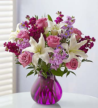 Pink roses and white lilies in a purple glass vase