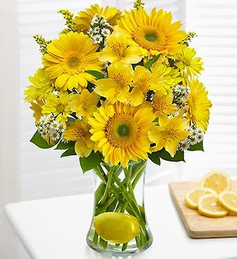 Yellow daisy bouquet in a clear vase with lemon slices