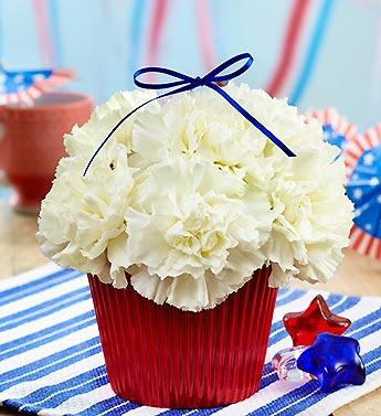White carnations in a red container with a blue ribbon bow