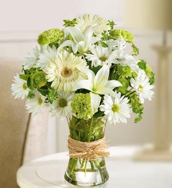 White daisies and lilies arranged in a glass vase with twine wrap