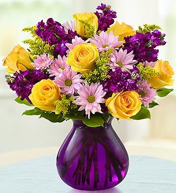 Yellow roses and pink daisies in a purple vase