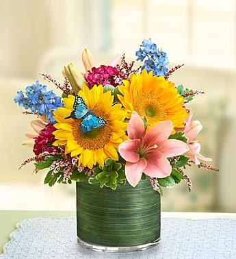 Sunflowers and pink lilies in a green glass vase