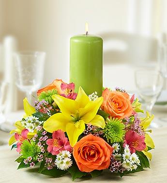 Floral centerpiece with a green pillar candle and bright mixed blooms