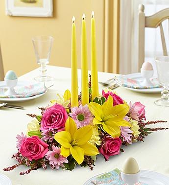 Floral table centerpiece with yellow candles and pink and yellow flowers