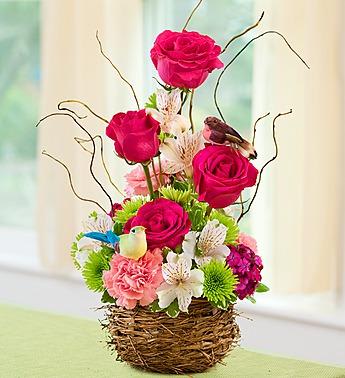 Pink roses and mixed flowers in a woven basket with bird decorations