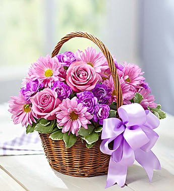 Pink and purple flowers in a wicker basket with a lavender ribbon