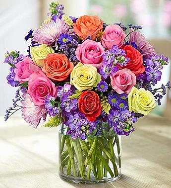 Mixed bouquet of roses and purple flowers in a glass vase