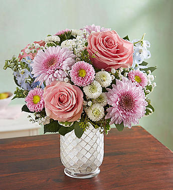 Pink roses and daisies arranged in a clear glass vase