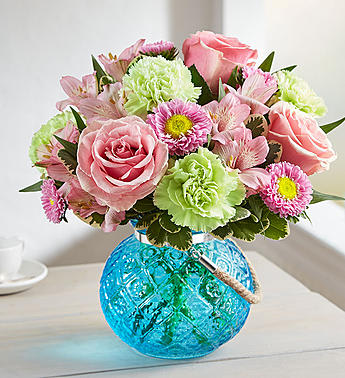 Pink roses and mixed flowers in a blue glass vase