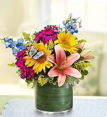 Colorful bouquet with sunflowers, lilies, and blue flowers in a green vase