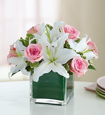 Pink roses and white lilies arranged in a clear square vase