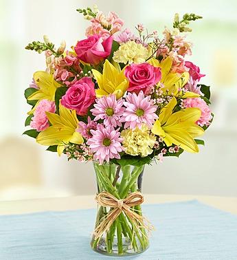 Bouquet of pink and yellow flowers in a clear glass vase