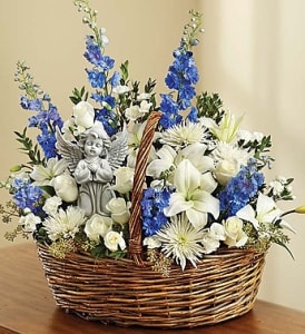 Basket arrangement of white and blue flowers with a small angel figurine