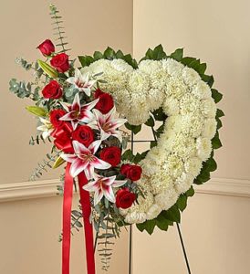 Heart-shaped floral wreath with red roses and white blooms on an easel