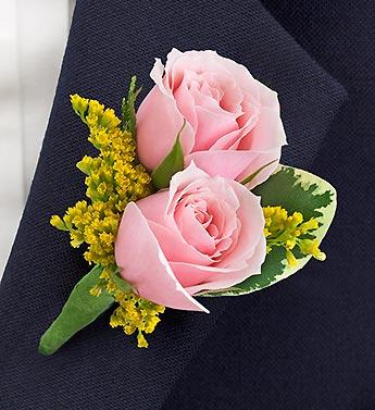 Pink rose boutonniere with yellow filler flowers on dark fabric