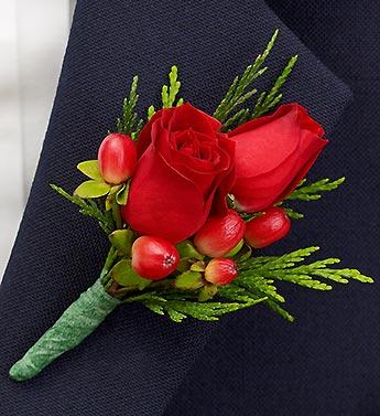 Red rose boutonniere with green accents on dark fabric