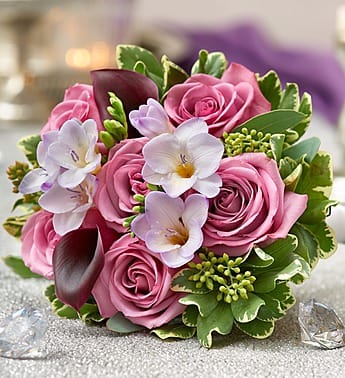 Pink roses with white orchids and dark calla lilies in a compact bouquet