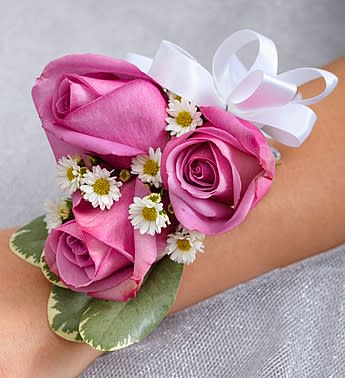 Pink rose wrist corsage with small white daisies and a white ribbon bow