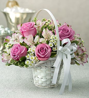 Pink roses and white alstroemeria in a white basket with a ribbon bow