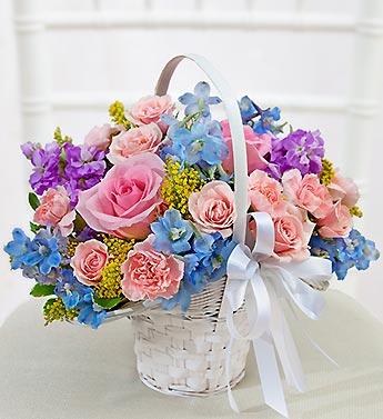 Basket of pink and blue flowers with a white ribbon bow
