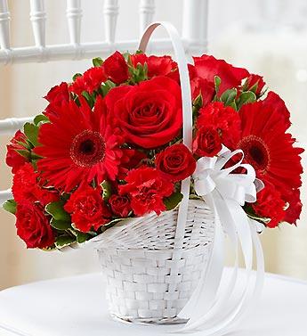 Red roses and gerbera daisies in a white basket with a ribbon