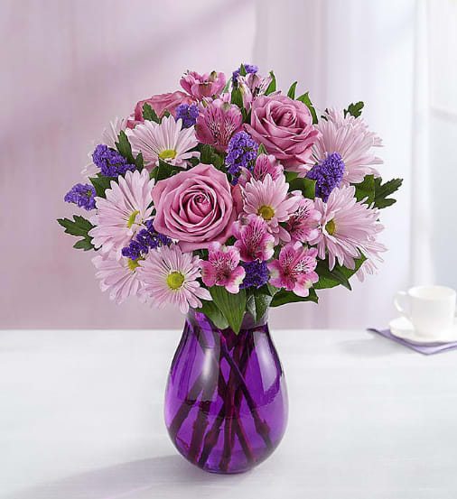 Pink and purple mixed bouquet in a purple glass vase