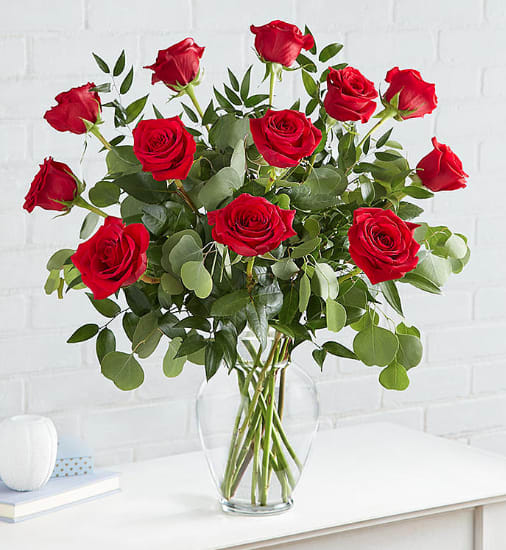 Red roses in a clear glass vase with mixed greenery