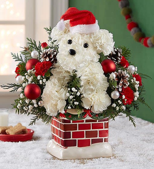 White teddy bear floral arrangement with a Santa hat in a brick-pattern planter
