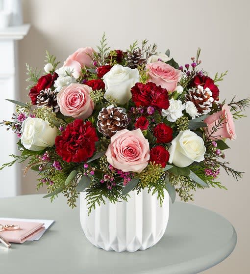 Pink and white roses with red carnations in a white vase