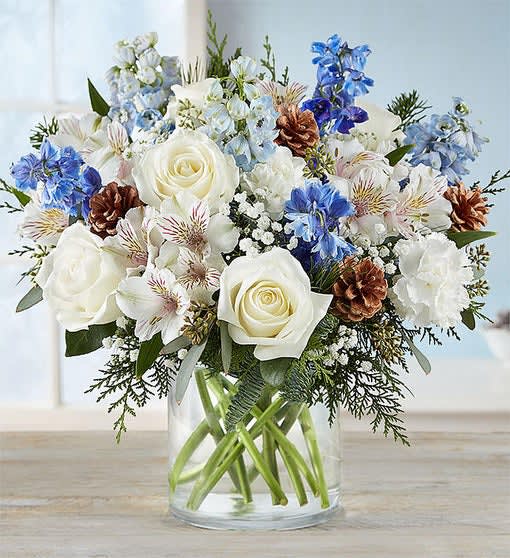 White roses and blue flowers arranged in a clear glass vase