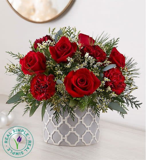 Red roses and carnations in a patterned white vase