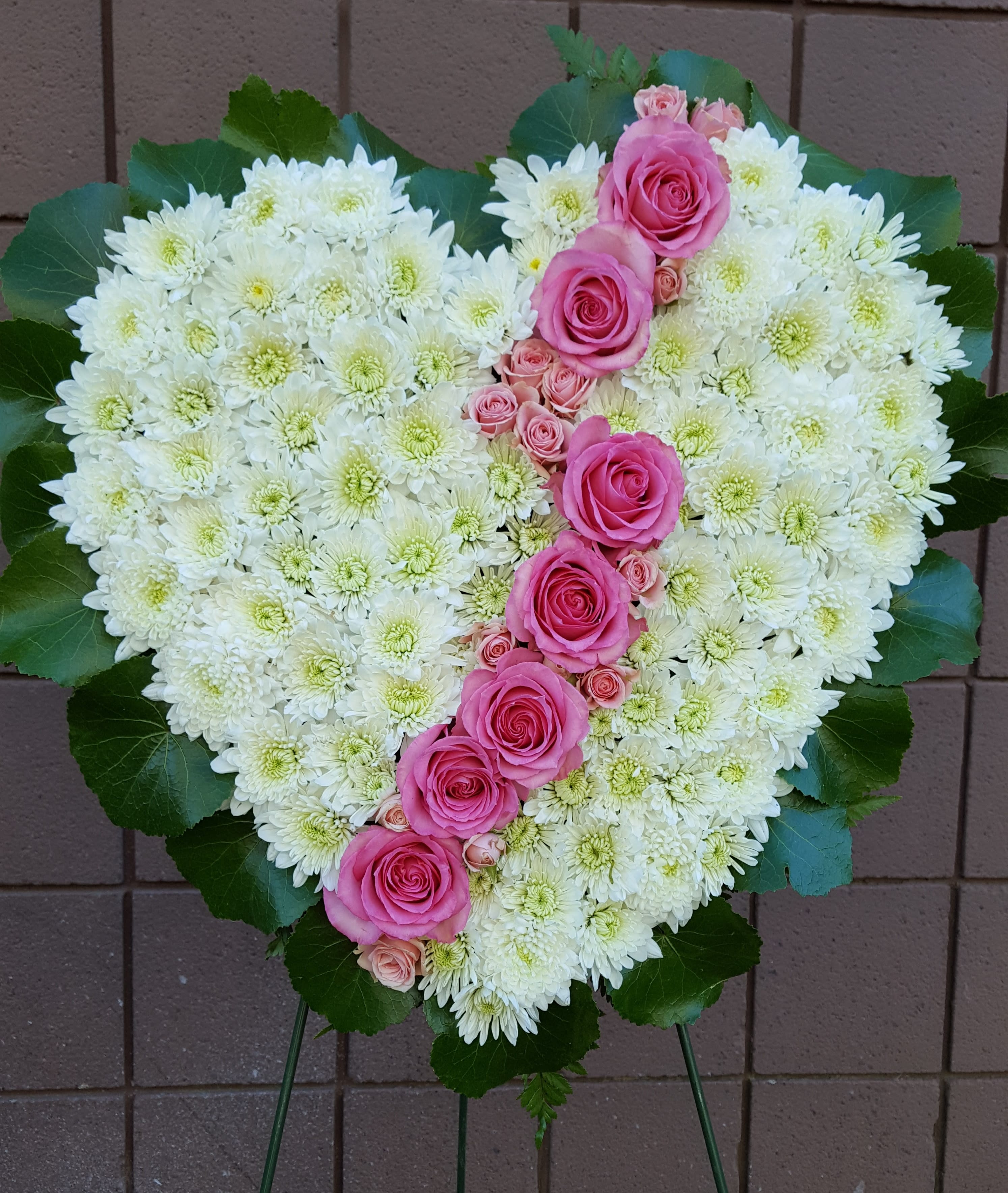 Heart-shaped floral spray of white chrysanthemums and pink roses on a stand