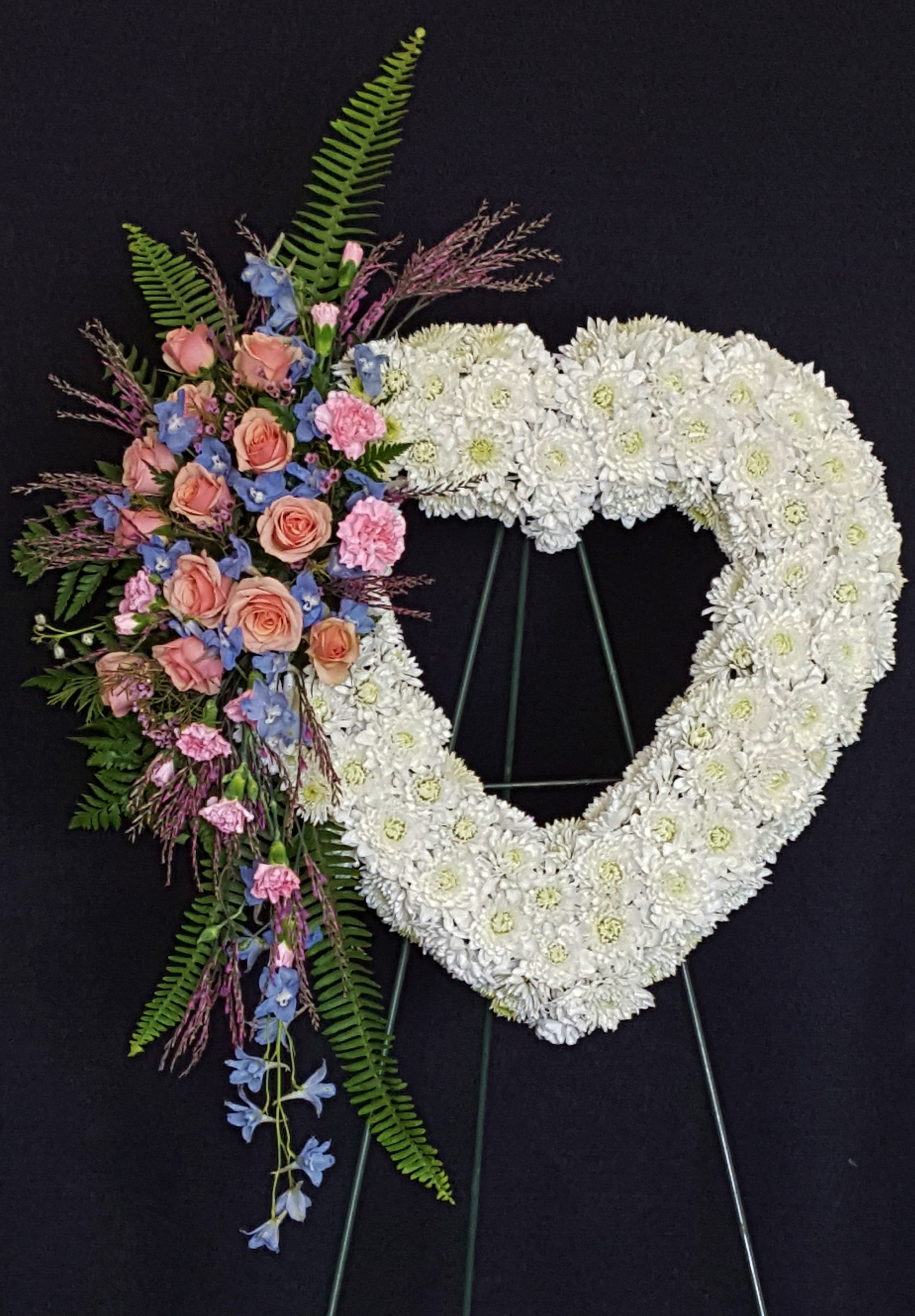 Heart-shaped white floral wreath with a pink and blue flower spray